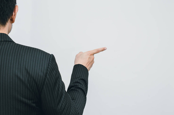Azjatycki biznes człowiek wskazując palcem dotknąć lub zamówić polecenia Widok z tyłu na biały znak - Zdjęcie, obraz
