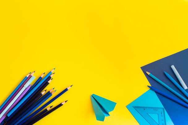 Creative, fashionable, minimalistic, school or office workspace with blue supplies on yellow background. Flat lay. - Foto, afbeelding