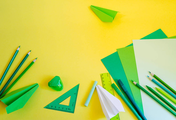 kreative, modische, minimalistische, Schul- oder Büroarbeitsplätze mit grünem Material auf gelbem Hintergrund. flache Lage. - Foto, Bild