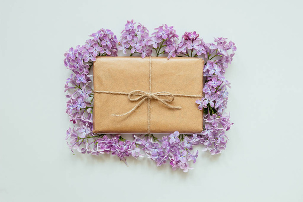 Χαριτωμένο δώρο κουτί τυλιγμένο με χαρτί κραφτ και λιλά λουλούδια κορυφή vie - Φωτογραφία, εικόνα