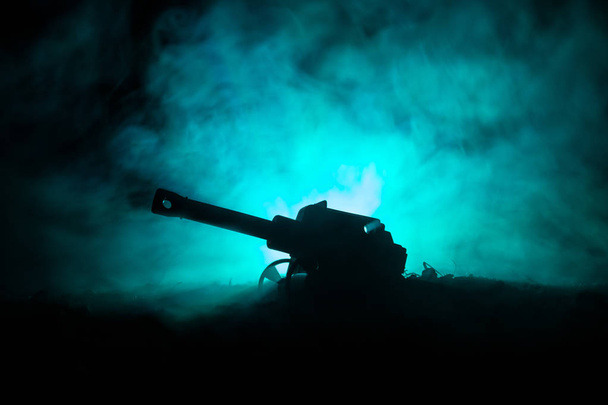 Battle scene. Silhouette of old field gun standing at field ready to fire. With colorful dark foggy background - Photo, Image