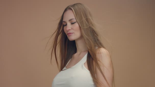 Schönheit Frau Modell im Studio auf beigem Hintergrund mit Wind im Haar erröten es - Filmmaterial, Video