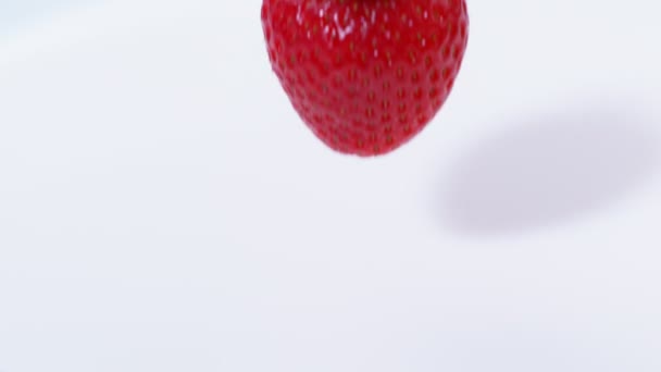 4K Fresh red strawberry dropping into bowl of cream, close up in slow motion - Imágenes, Vídeo