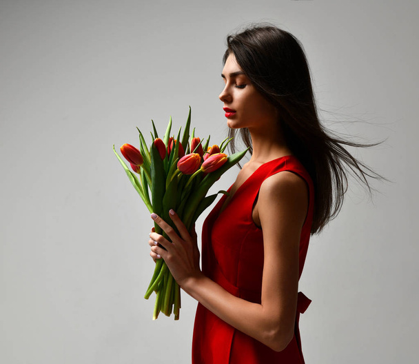 Beautiful woman with bouquet of tulip flowers in red dress and little sticker on tulips  - Fotografie, Obrázek