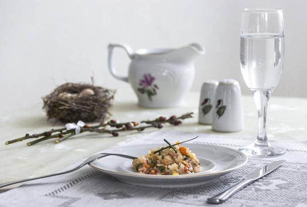 on the table napkin with a plate vegetable stew green onion glass fork knife and willow branches with quail eggs salt pepper sauce  - Фото, изображение
