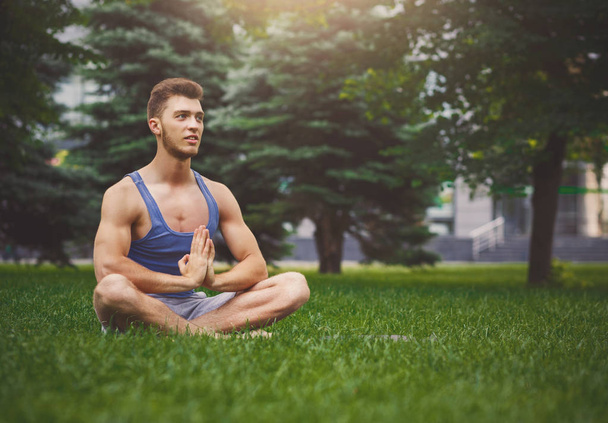 Молодой человек практикующий йогу сидя в падмасане
 - Фото, изображение
