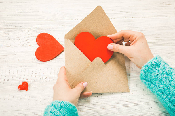 Hand eines Mädchens, das am Valentinstag Liebesbriefe schreibt. Handgefertigte Postkarte mit roter Herzfigur. 14 februar feiertag. Valentinstag-Konzept mit Kopierraum - Foto, Bild