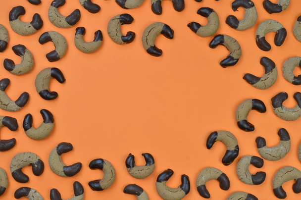 frame uit zelfgemaakte nougat halve manen koekjes met chocolade aan de randen op een oranje achtergrond - Foto, afbeelding