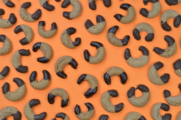 patroon van de achtergrond uit zelfgemaakte nougat halve manen koekjes met chocolade aan de randen op een oranje achtergrond  - Foto, afbeelding