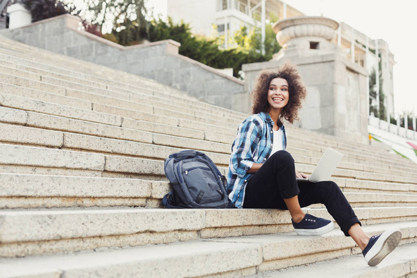 Улыбающийся студент сидит на лестнице с ноутбуком
 - Фото, изображение