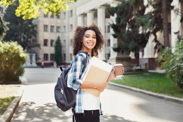 Student girl with backpack and workbooks at university building background - Photo, Image
