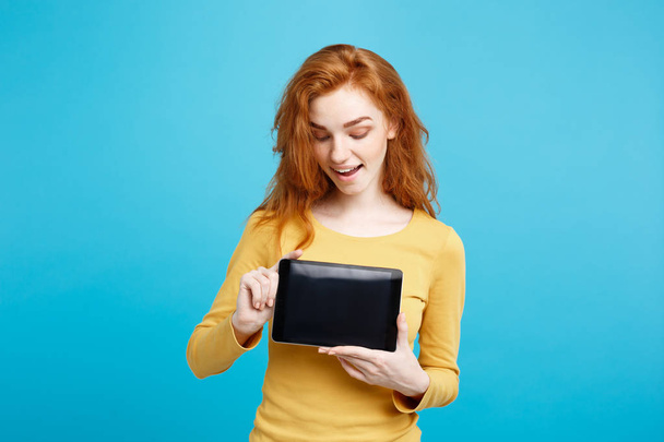 Business Concept - Close up Portrait young beautiful attractive redhair girl smiling showing digital tablet screen on black. Blue Pastel Background. - Photo, Image