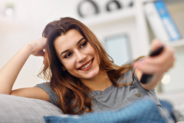 Schöne junge Frau entspannt sich zu Hause vor dem Fernseher - Foto, Bild