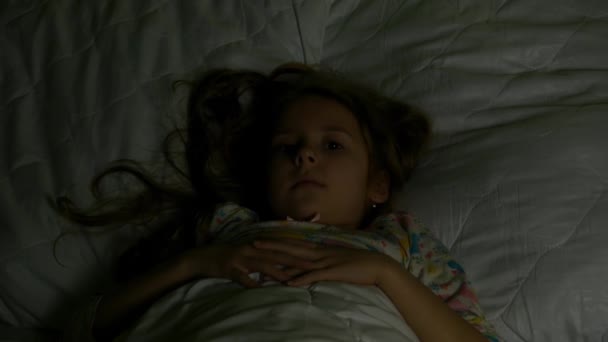 The child frightenedly hides under the blanket at night - Felvétel, videó
