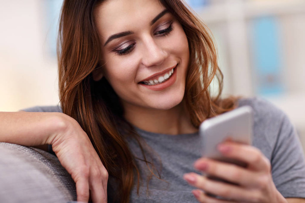 Happy adult woman using phone at home in the living room - Foto, Bild