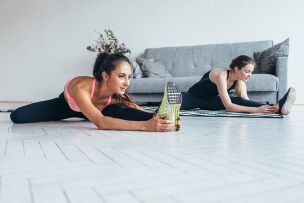 Evde katta oturan egzersiz germe yapmak önce ısınma-up kasları egzersiz sportswomen - Fotoğraf, Görsel