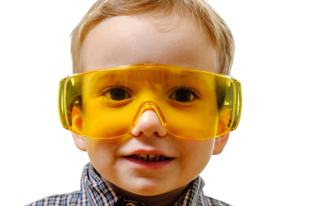 Concept, small smiling boy with protective glasses, looks afar isolated on white background with copy space - Foto, immagini