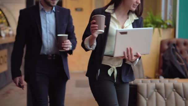 Girl and a guy in business suits sit down at a table with a laptop and coffee to discuss the details of the work - Video, Çekim