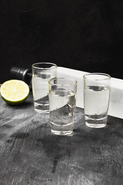 Cold vodka in shot glasses on a black background - Photo, Image
