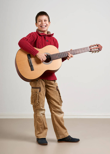 Boy having fun with guitar, making music and singing - Photo, Image