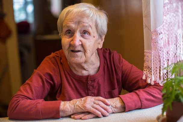Mujer anciana emocional sentada a la mesa
. - Foto, imagen