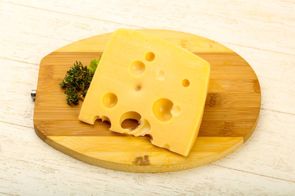 Pedazo de queso sobre el plato de madera
 - Foto, imagen