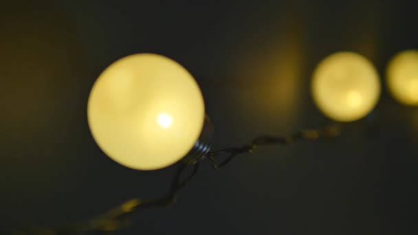 Light bulbs garland close up. Electric bulb shine hanging on wall as decoration for holiday close up - Footage, Video