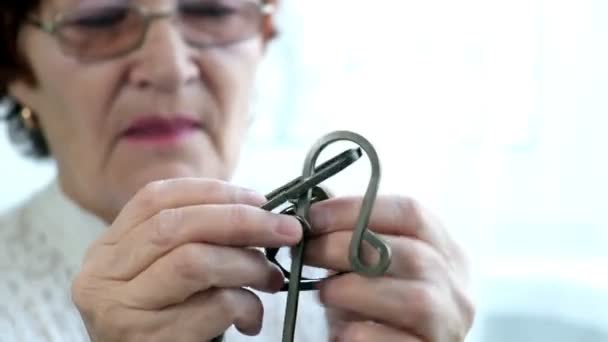 eine alte Frau löst ein Metallpuzzle auf, trainiert Gehirnaktivität - Filmmaterial, Video