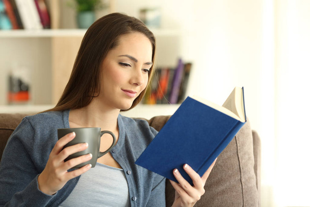 Relaxed lady reading a book and holding a mug - Фото, изображение