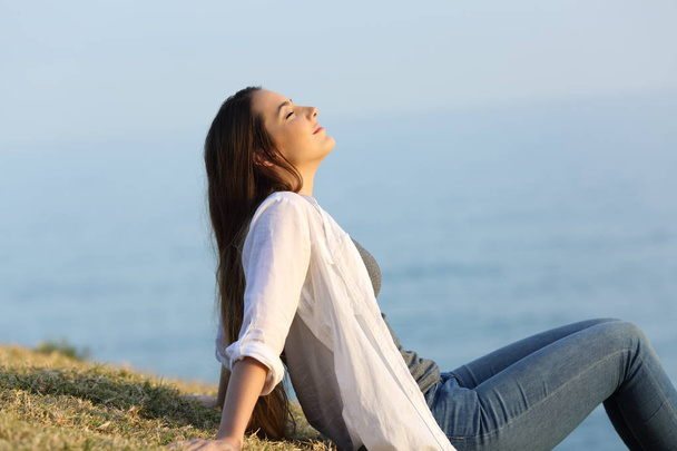 Relaxed woman breathing fresh air sitting on the grass - Photo, Image