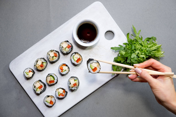 Vegan sushi rolls with quinoa, vegetables and soy-nut sauce on a white plate, light background. Vegan Healthy Food Concept. - Photo, image