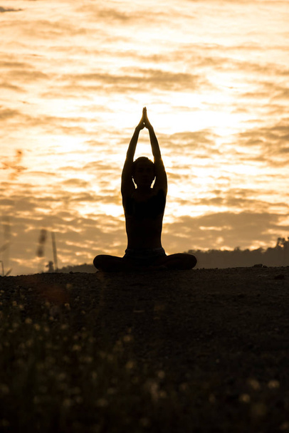 Sylwetka młoda kobieta praktykowania jogi na górze o zachodzie słońca - Zdjęcie, obraz