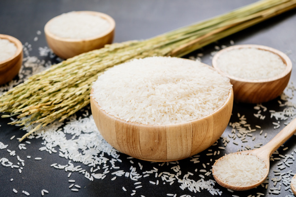 Сырой жасминовый рис в деревянной чаше и ложке с зерном и семенами
 - Фото, изображение