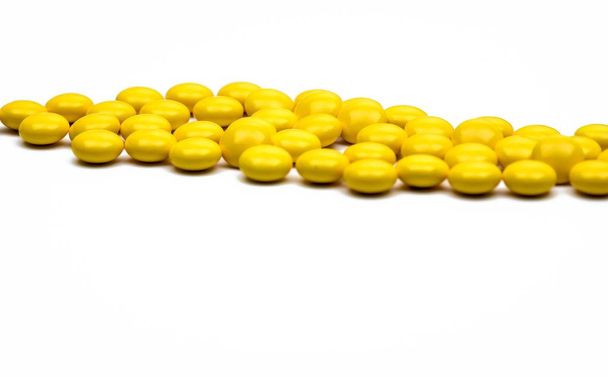 Macro shot detail of yellow round sugar coated tablets pills on white background with copy space for text. - Photo, image