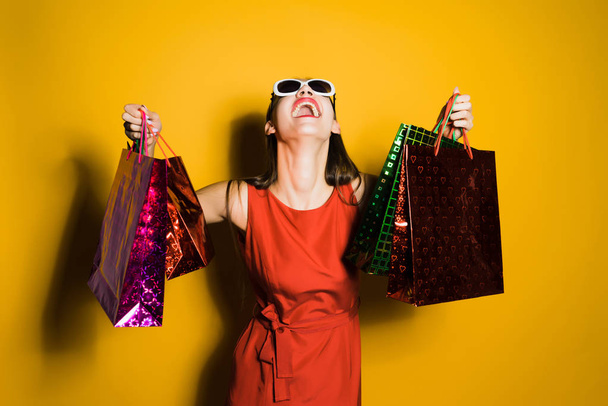 happy woman in red dress holding shopping bags - Zdjęcie, obraz