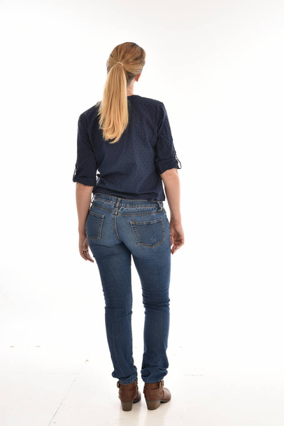портрет блондинки в простой синей рубашке и джинсах, стоящей лицом к камере. изолированные на белом фоне
. - Фото, изображение