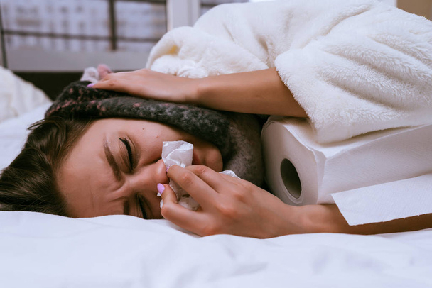 a sick woman lies on a bed and paper towels - Foto, Bild