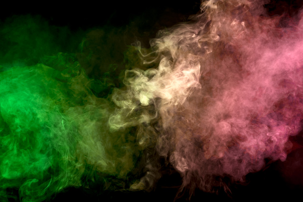 Thick colorful smoke of green  on a black isolated background. Background from the smoke of vape - Photo, Image