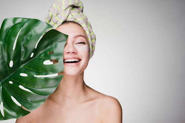 happy woman with a towel on her head after the shower has put patches under the eyes - Foto, imagen