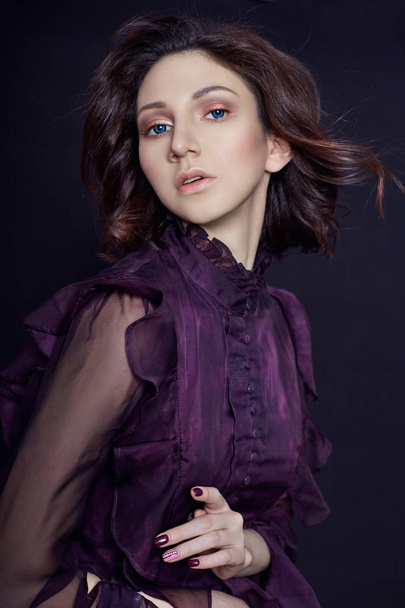 Contrast fashion Armenian woman portrait with big blue eyes on a dark background in a purple dress. Lovely gorgeous girl posing in evening dress. Bright makeup, woman. - Foto, Imagen