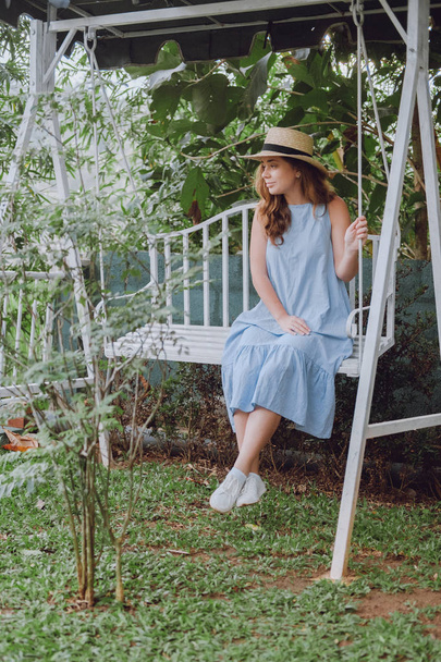 Young woman in a hat sits on a swing - Photo, image