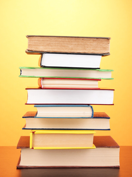 Стек цікавих книг і журналів на дерев'яному столі на помаранчевому фоні
 - Фото, зображення