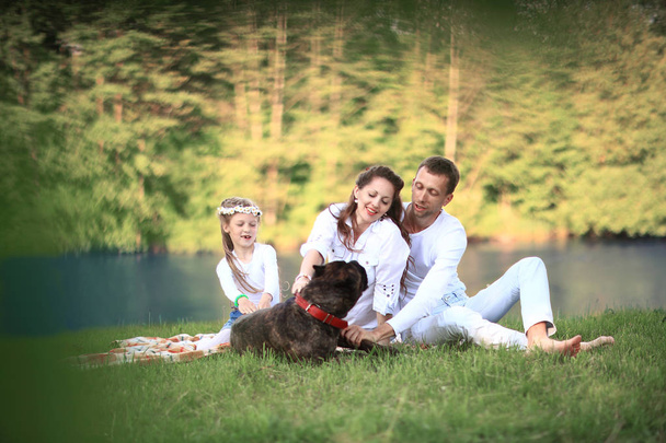 happy family with pet dog at picnic in a Sunny summer day. pregn - 写真・画像