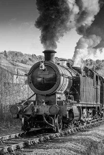 Photographie verticale verticale en noir et blanc d'une vieille locomotive à vapeur gonflant beaucoup de fumée
 - Photo, image