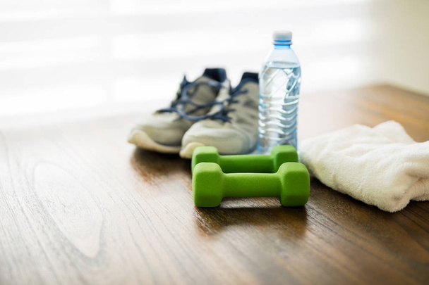 Concept de forme physique et de mode de vie actif. Haltères, chaussures de sport, bouteille d'eau et serviette sur table en bois
 - Photo, image