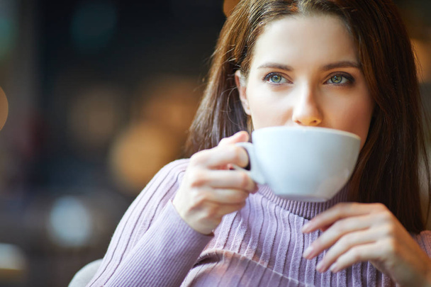 Beautiful young woman with a cup of tea at a cafe - Foto, immagini
