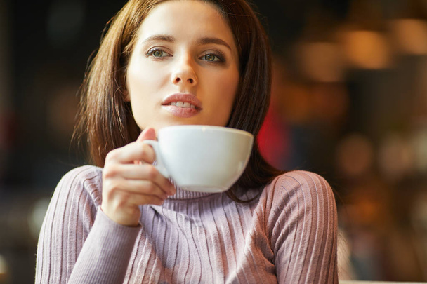 Beautiful young woman with a cup of tea at a cafe - Fotó, kép