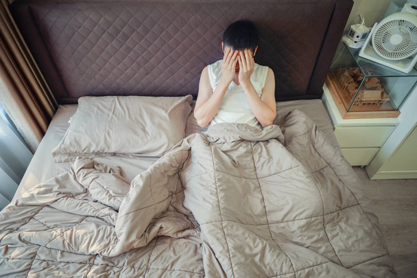 Depressed Asian man blaming on the phone on bed - Photo, Image