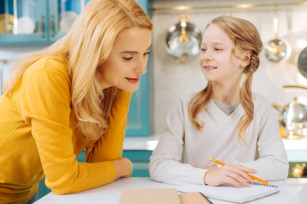 Inspired mother helping her daughter with homework - Foto, Bild