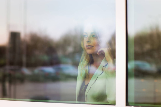 successful business woman looks out the window of his office - 写真・画像
